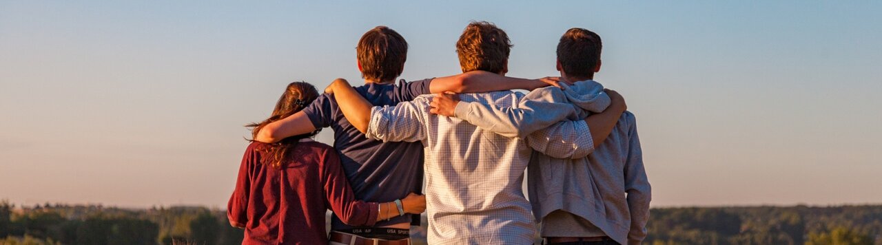 Vier Jugendliche welche sich an den Schultern halten
