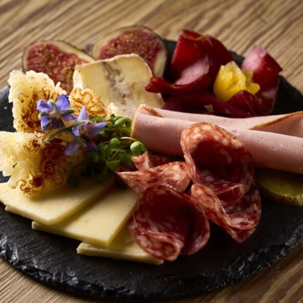 Fleisch- und Käse-Plättli, serviert auf rundem Schieferstein