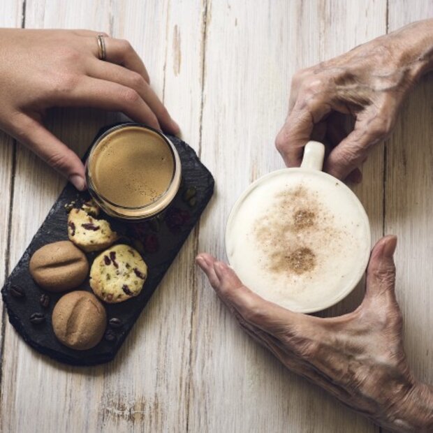 Junge und alte Hände halten eine Tasse Espresso und Cappuccino